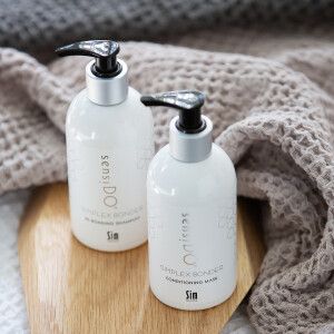 SIM shampoo- ja hoitoainepullo sekä pyyhe pöydällä